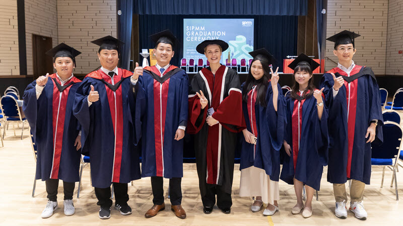 SIPMM graduates in gowns with a member of the academic procession at a graduation ceremony